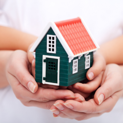 Foto com uma casa sobre diversas mãos juntas para anunciar as opções de financiamentos de imóveis.